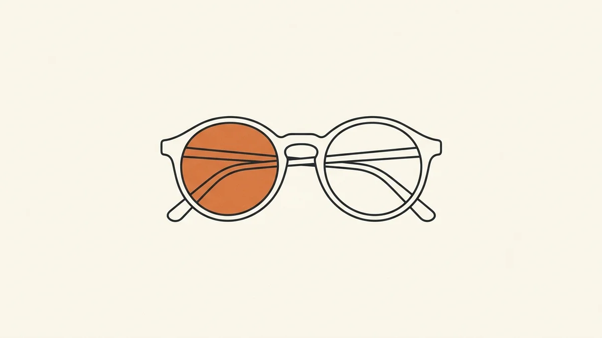 A pair of spectacle frames and a lens resting on a plain desk, photographed from directly above
