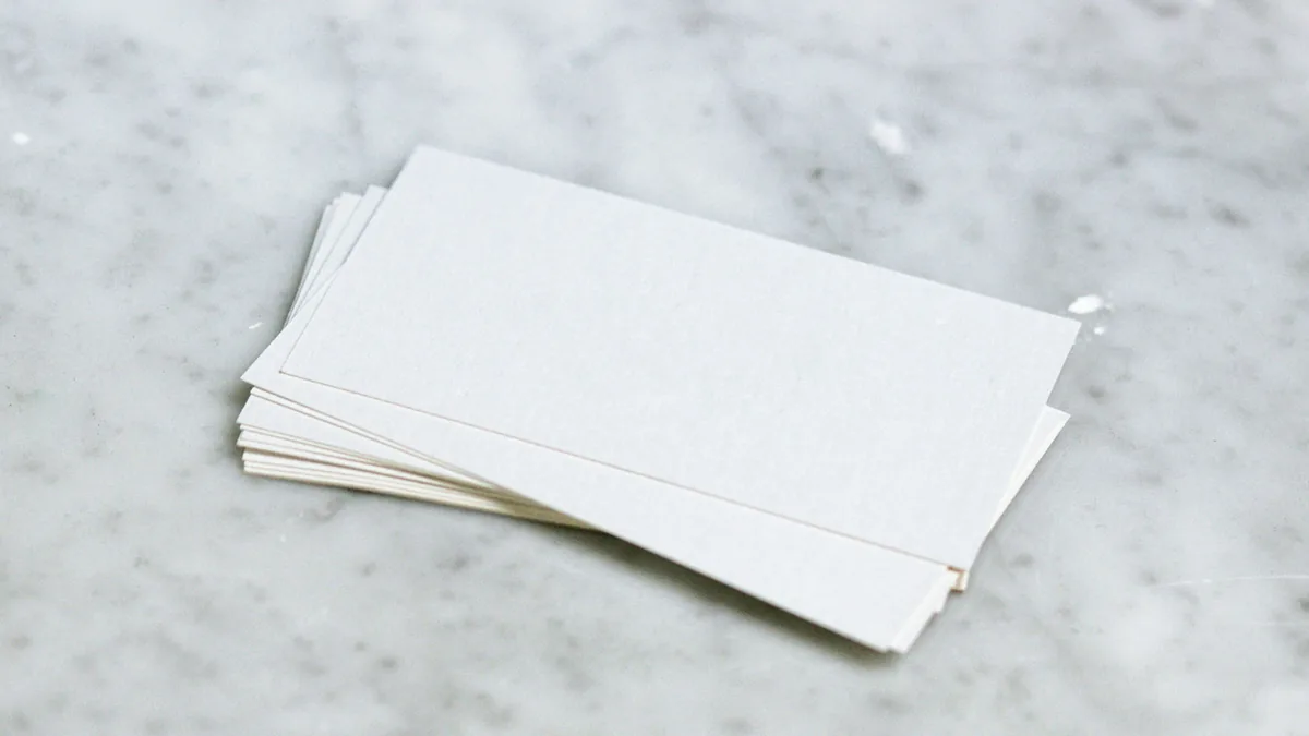 A small stack of blank white index cards fanned out on a pale marble surface