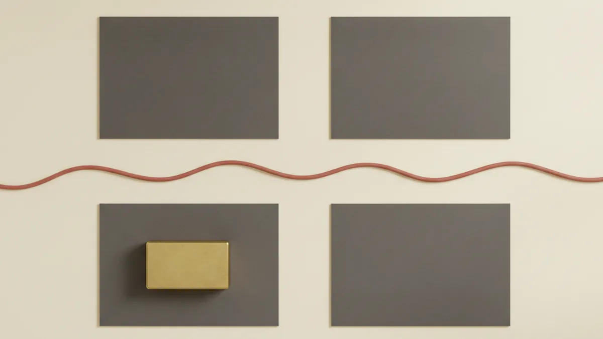 Four blank charcoal cards on a cream desk, one held down by a brass paperweight, with a terracotta cord running between them